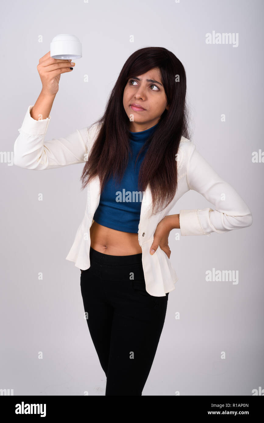 Studio shot of young Persian businesswoman standing while holdin Stock Photo