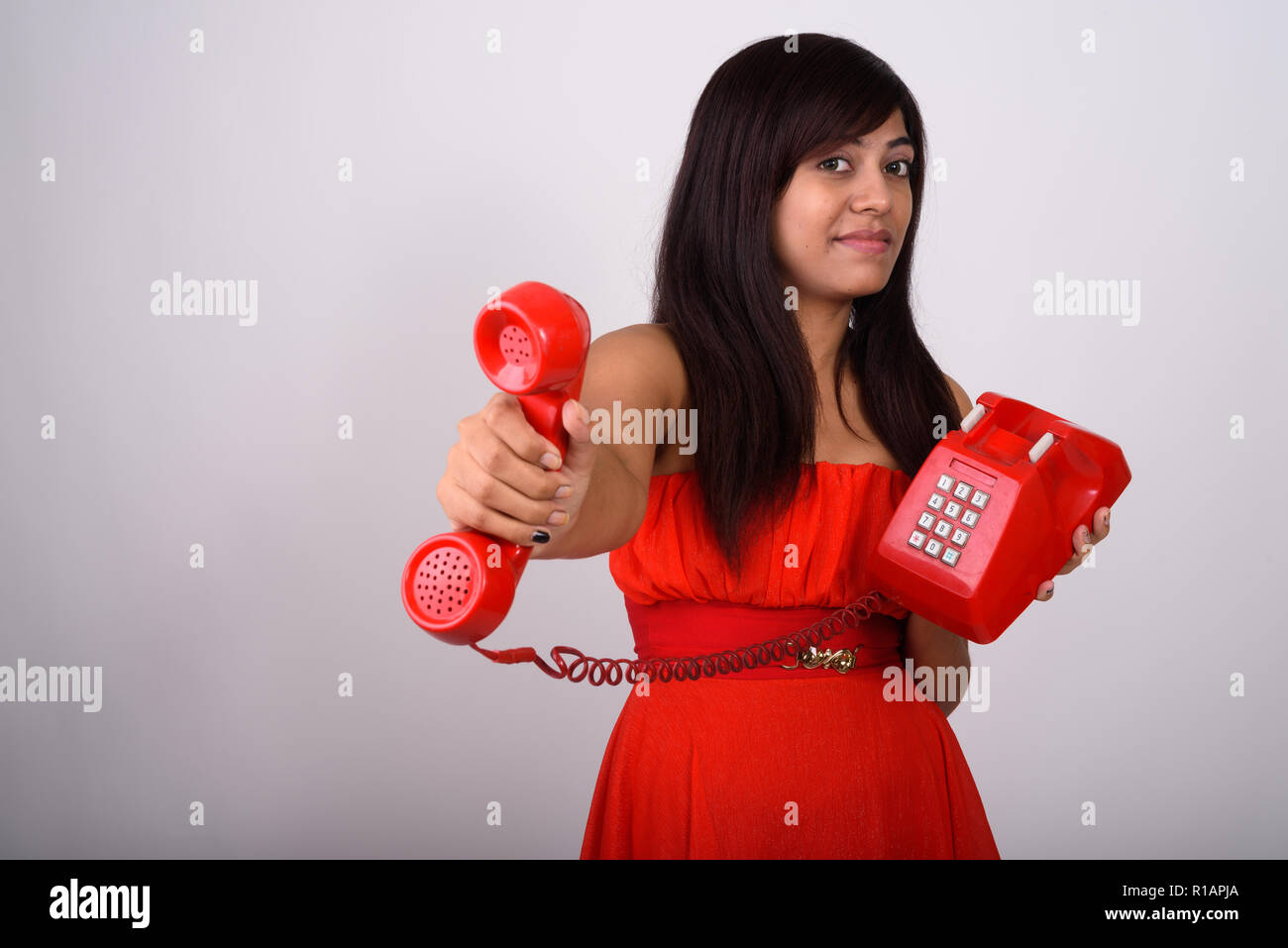 Studio shot of young Persian woman giving old telephone against  Stock Photo