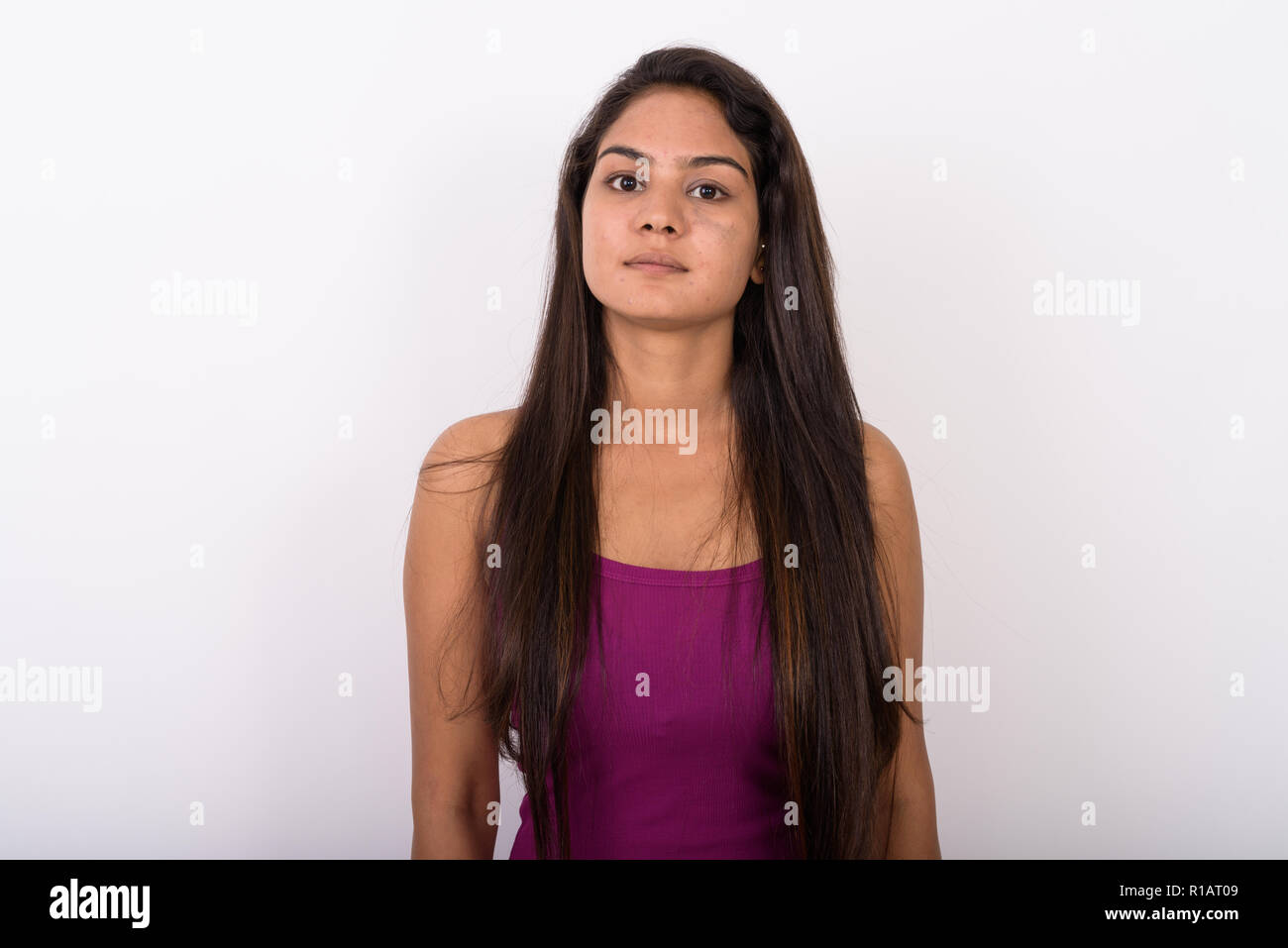 Studio shot of young Indian woman wearing sleeveless against whi Stock Photo