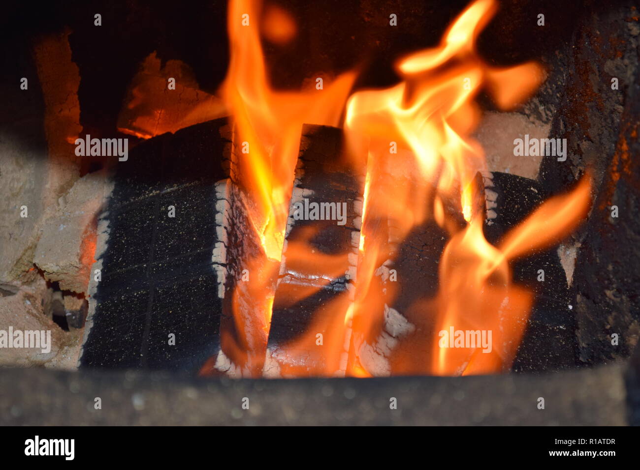 Close up of Brown Coal Briquettes on fire with red yellow flames inside