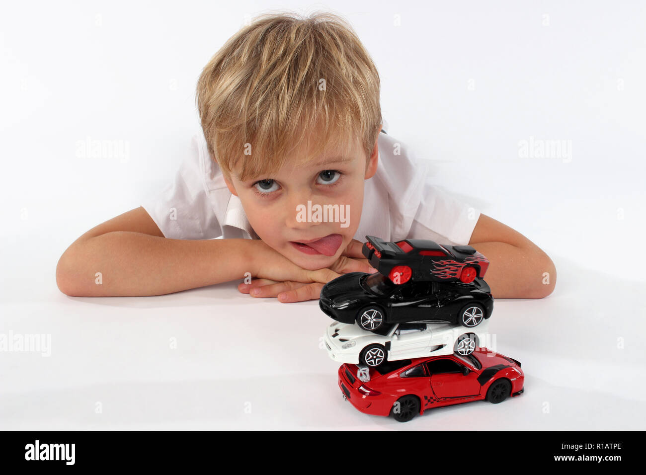 Child boy playing with toy cars in a studio, building a tower Stock Photo