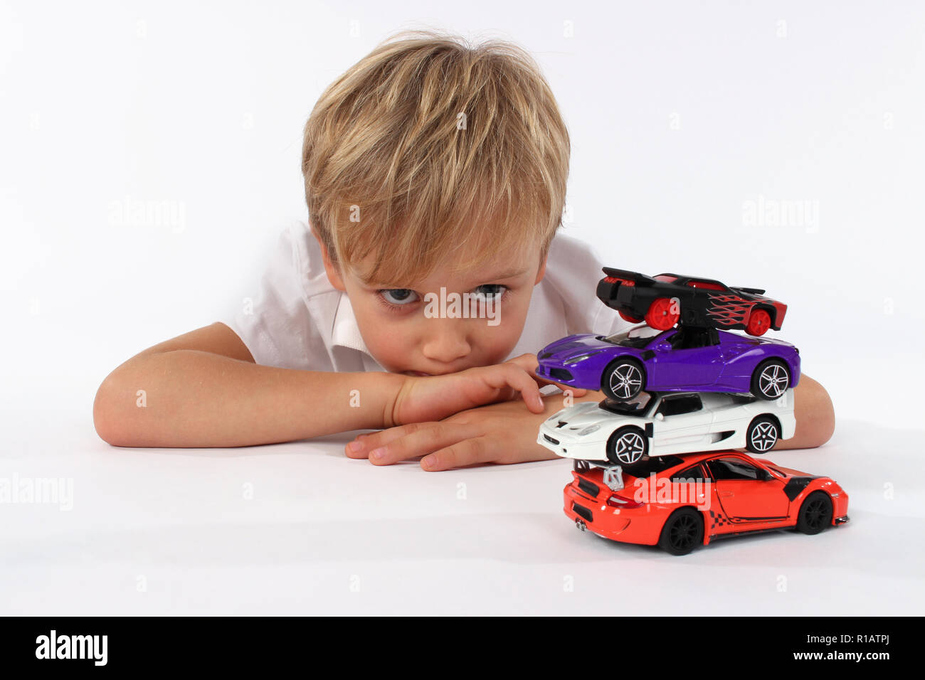 Child boy playing with toy cars in a studio, building a tower Stock Photo