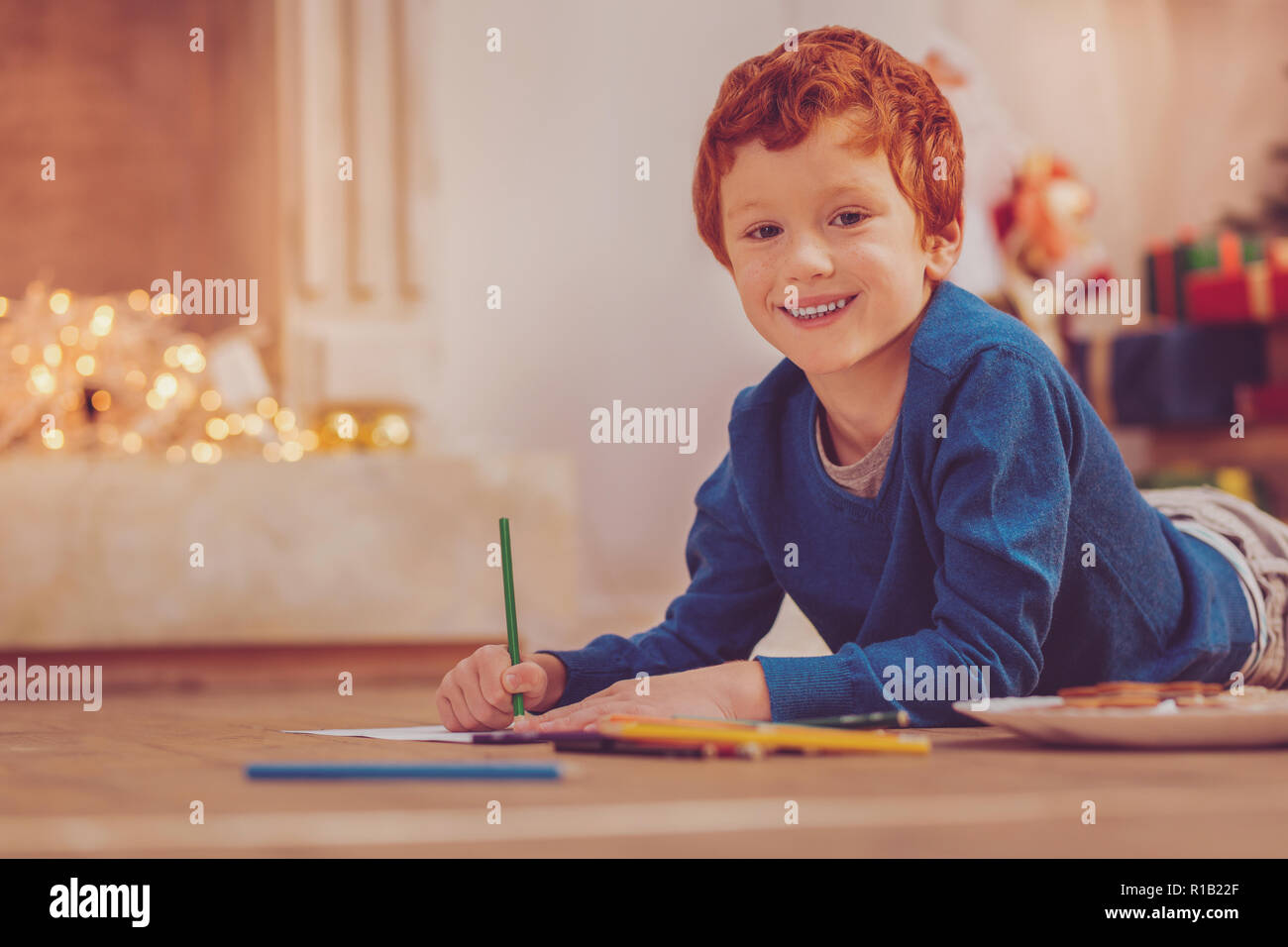 Cheerful boy drawing with pencils while lying on floor Stock Photo - Alamy