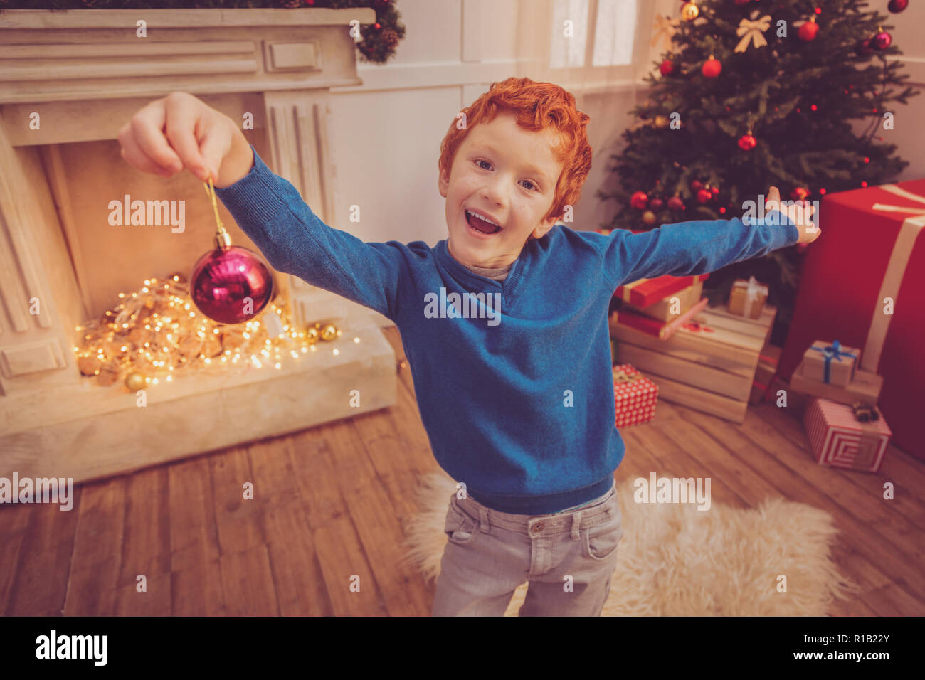 Cheerful red-haired boy posing with a Christmas ball Stock Photo