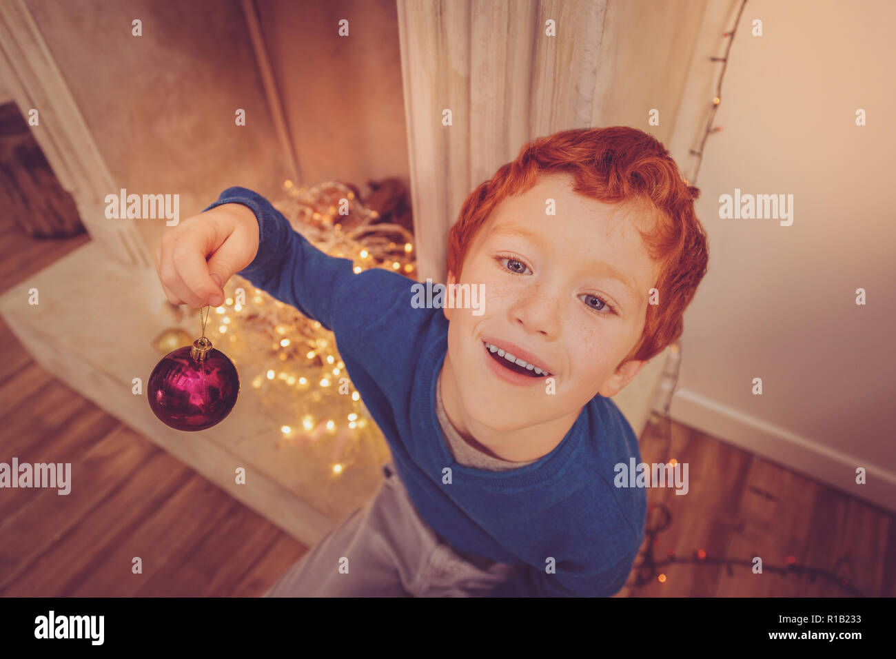 Top view of cute ginger-haired boy holding Christmas ball Stock Photo