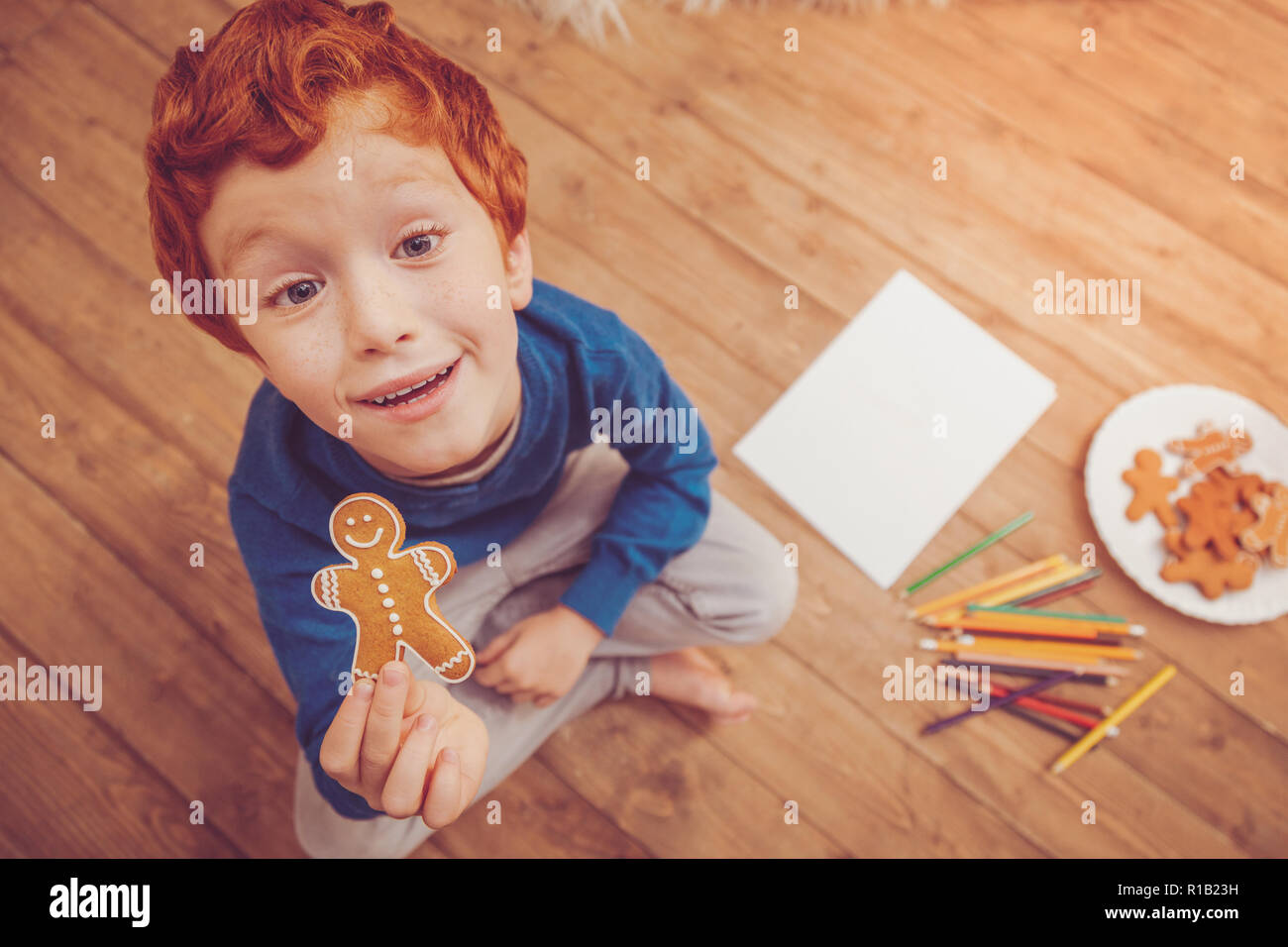 Top view of red-haired boy posing with gingerbread man Stock Photo