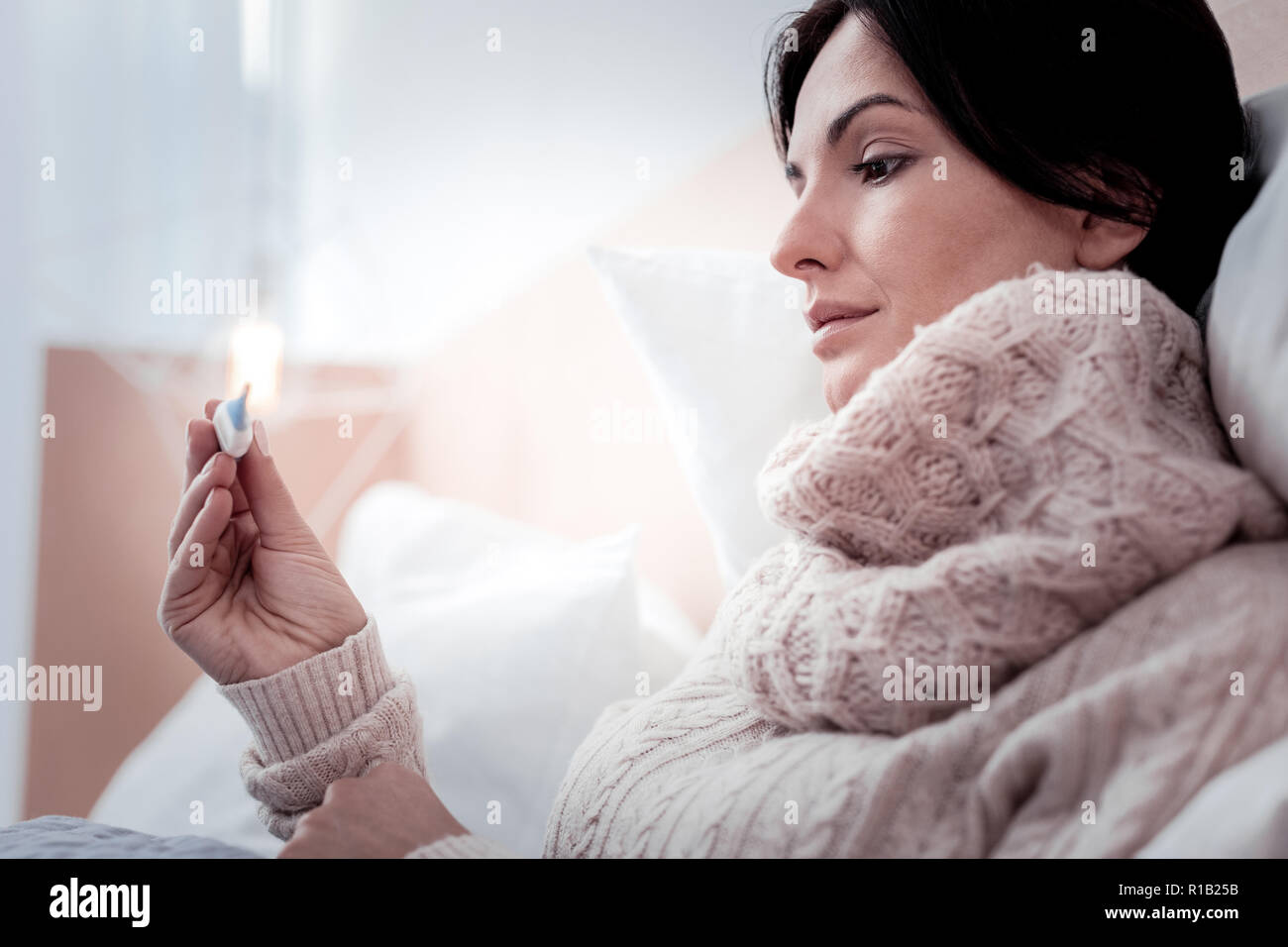 Close up of peaceful woman holding thermometer in hands Stock Photo