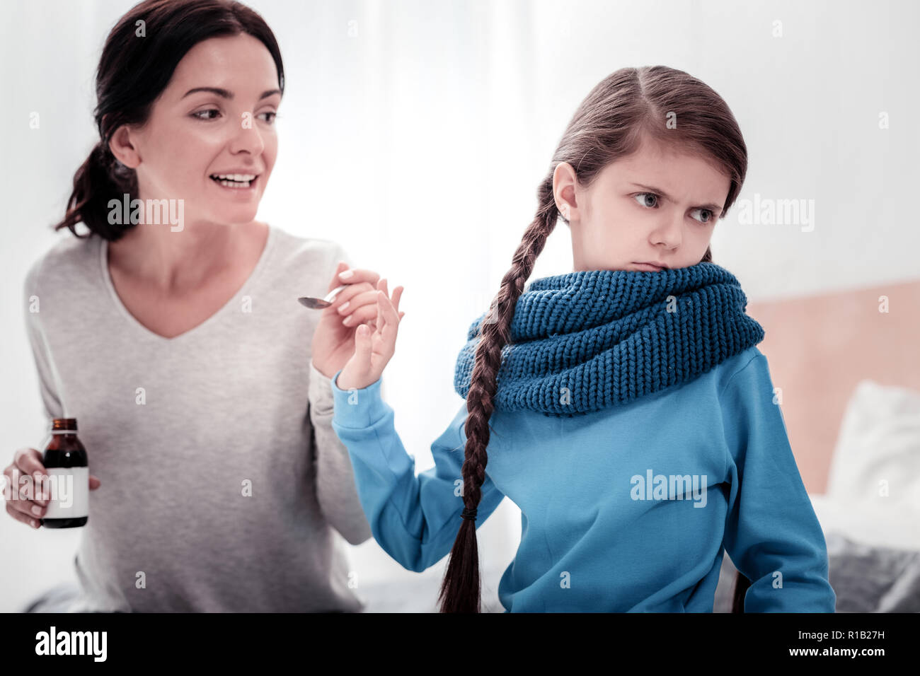 Careful mother with cough syrup and disobeying child Stock Photo