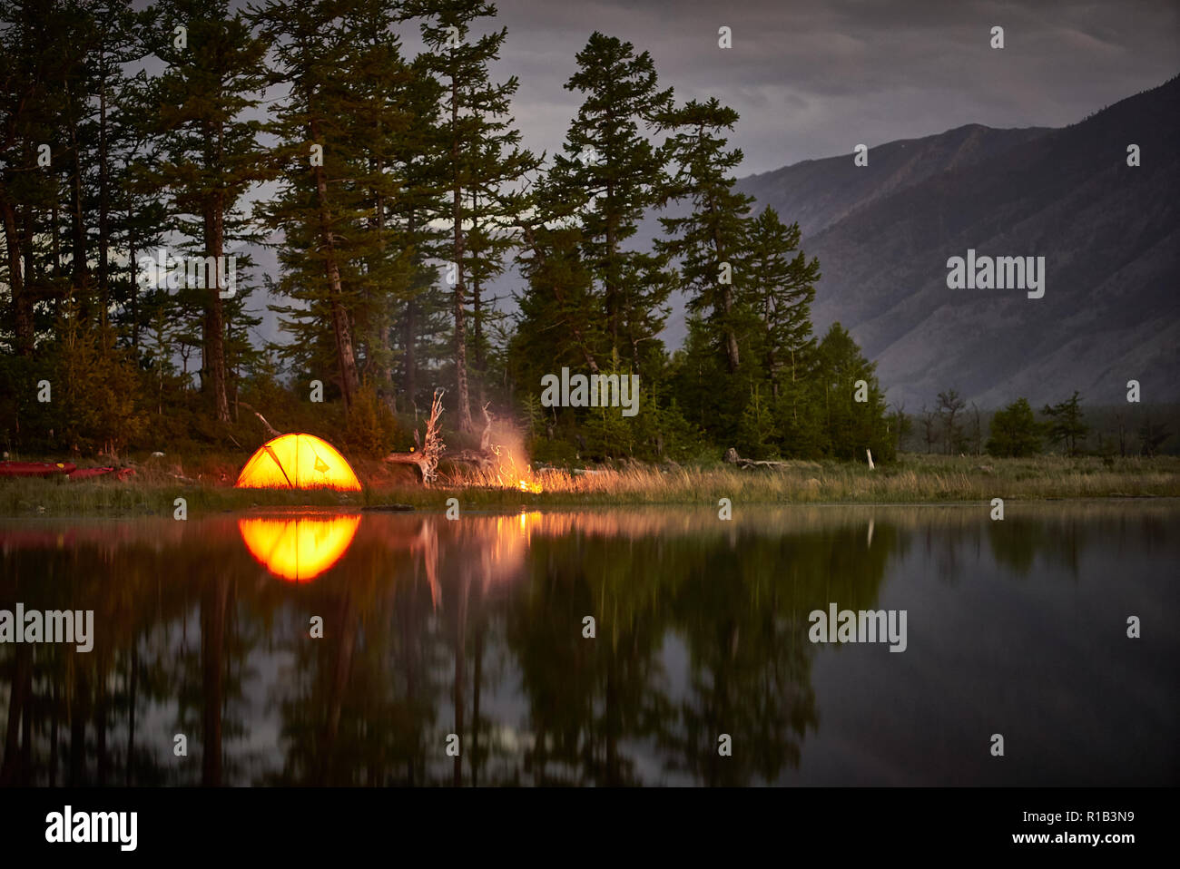 Orange tent on coast of lake at night. Stock Photo