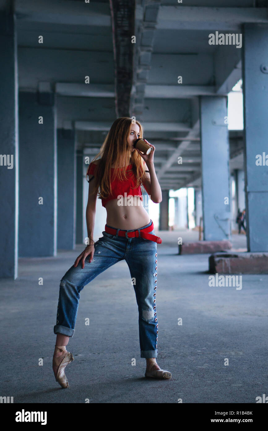 Ballerina dancing with a cup of coffee in jeans, t-shirt and pointe. Street  performance. Modern ballet. Slender girl holding a paper cup with a hot dr  Stock Photo - Alamy