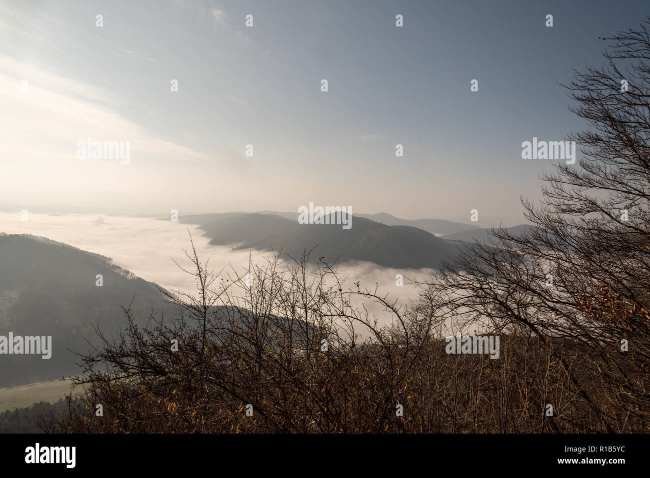 autumn mountain landscape with mist on Vah river valley, mountain ranges and blue sky from Klapy hill in Javorniky mountains near Povazska Bystrica ci Stock Photo