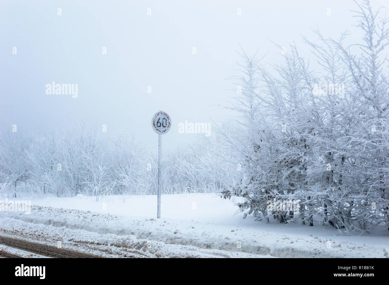 Speed limit traffic sign covered with ice and snow on snowy winter background Stock Photo