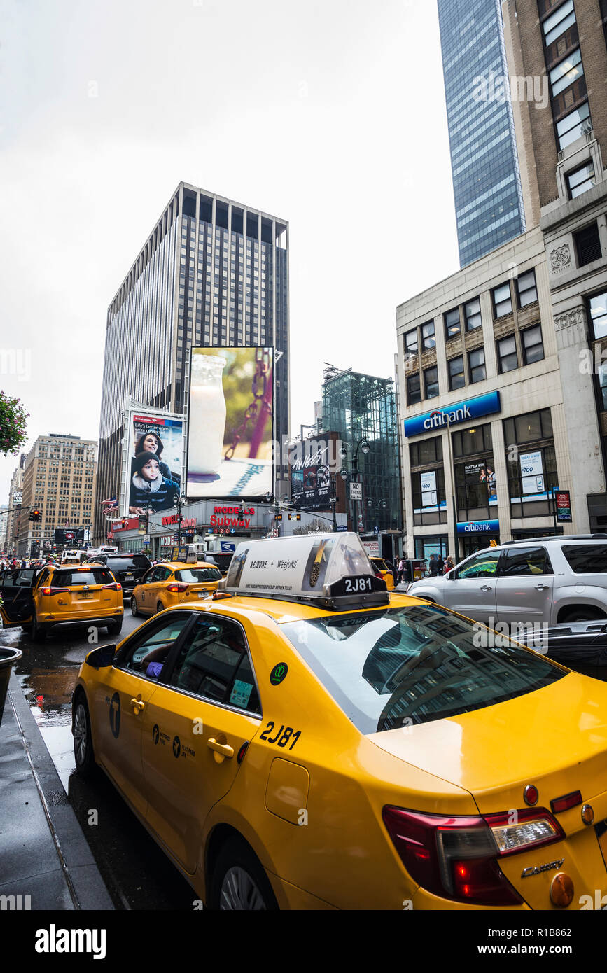 New York City, USA - July 25, 2018: Taxis parked in a row in Seventh Avenue and 34th Street with huge advertising screens and people around in Manhatt Stock Photo