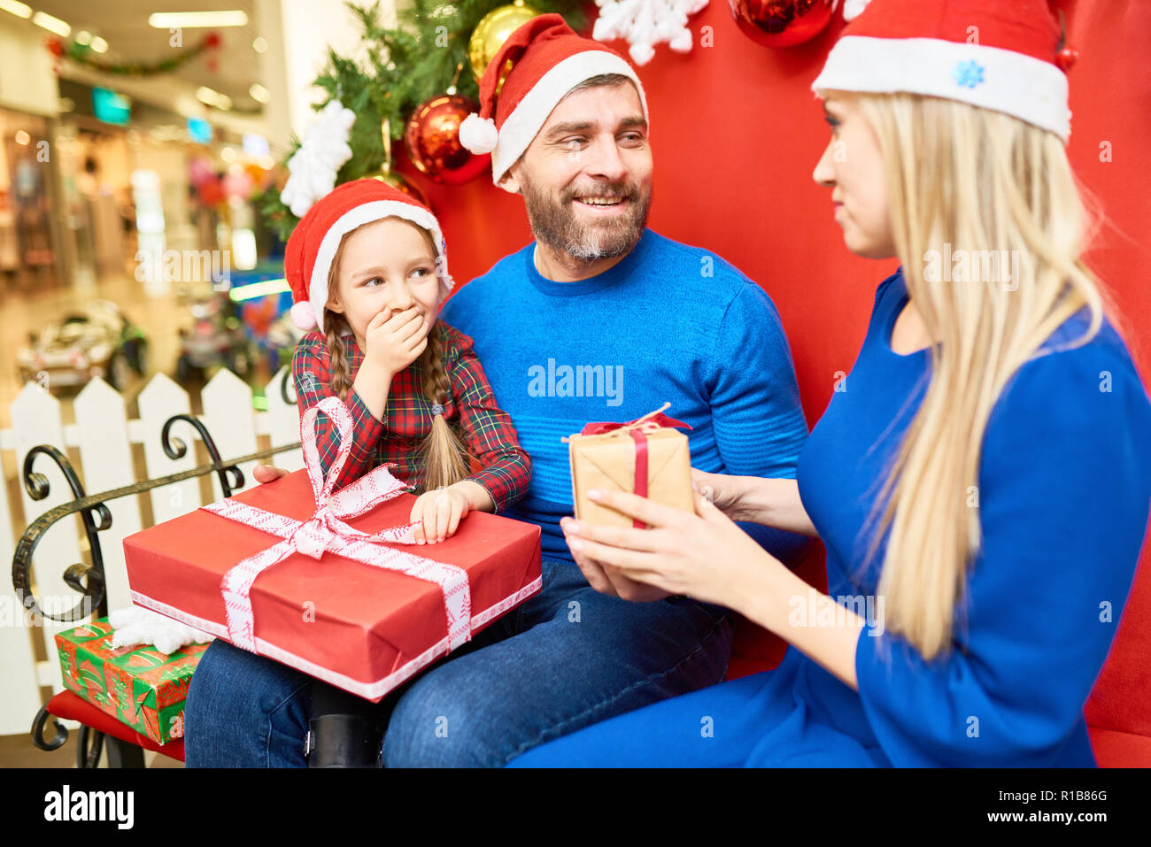 Cheerful family exchanging with presents in mall Stock Photo