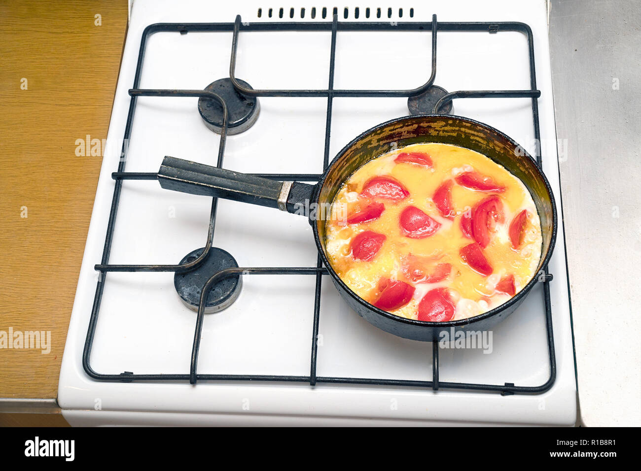 Fried eggs with tomatoes in a pan on gas stove Stock Photo Alamy