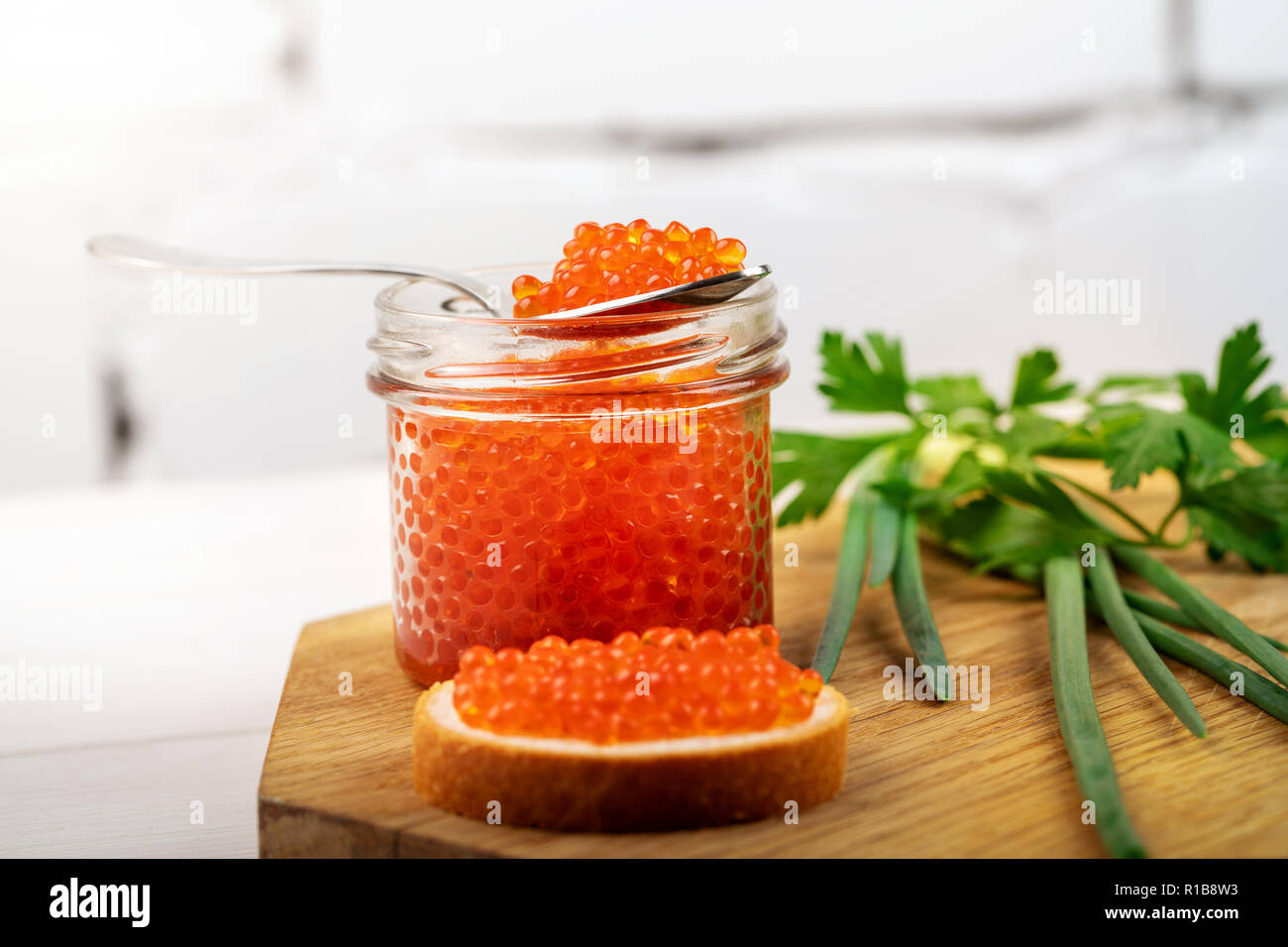 caviar appetizer - jar with red roe and herbs on the table Stock Photo