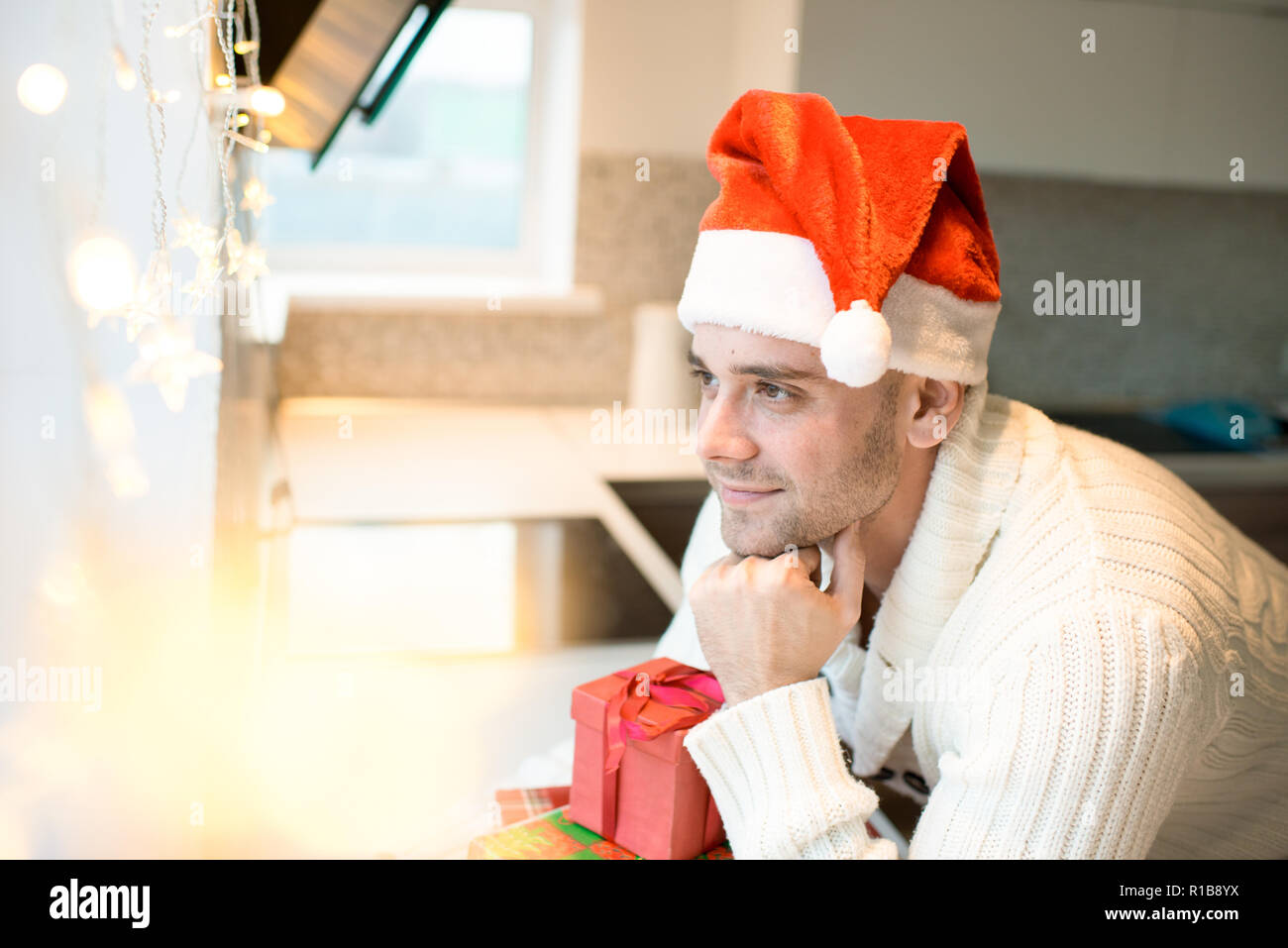 Dreamy man in Santa hat looking away Stock Photo