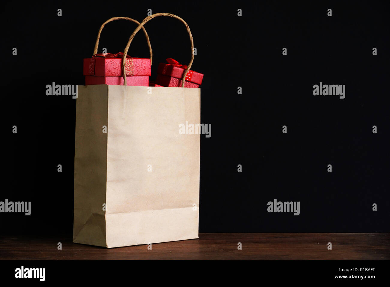 Tree red gift box in shopping bag on black background for shopping theme. Stock Photo