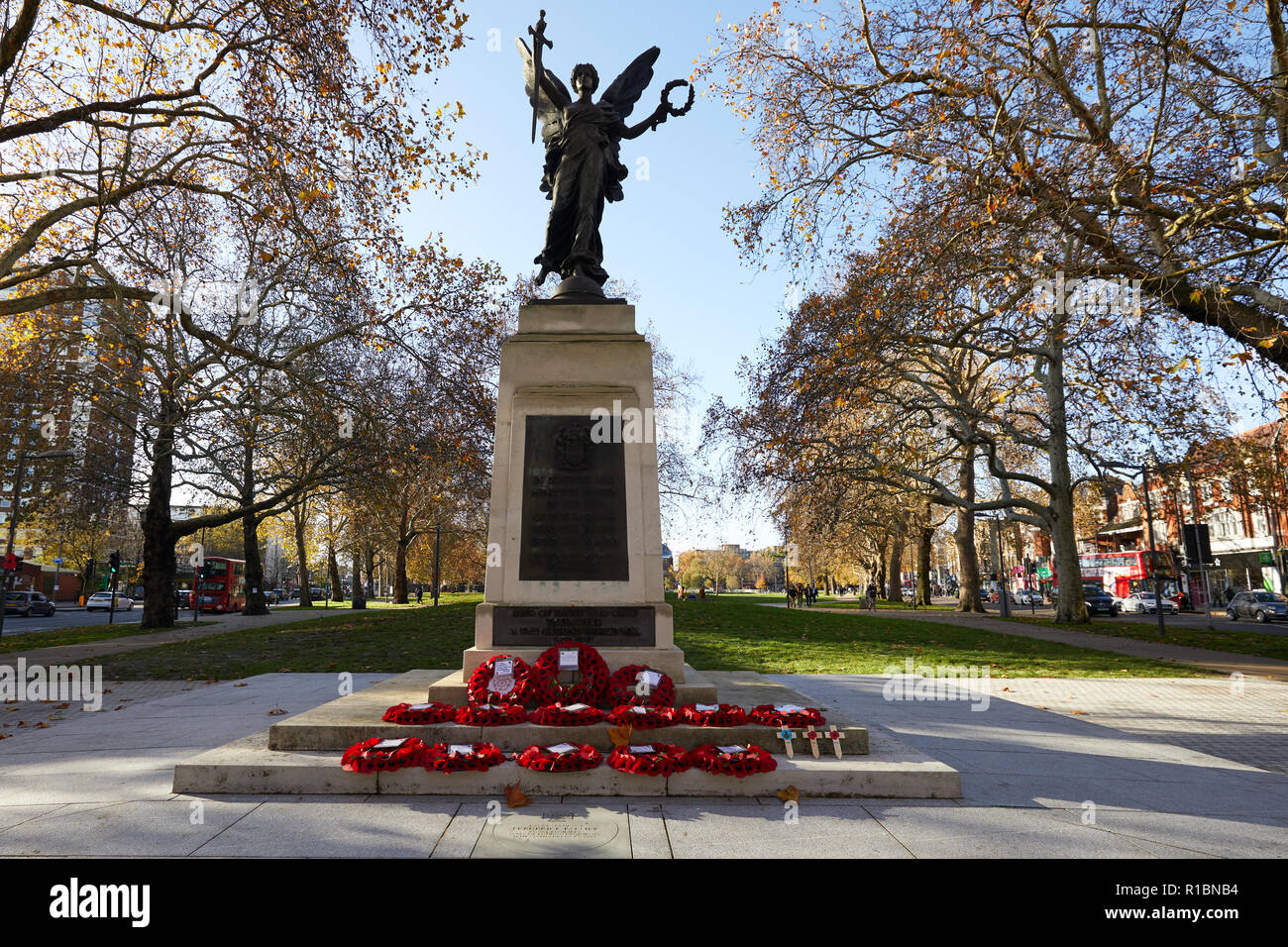 London, UK. - 11 November 2018: Poppy wreaths left at the Hammersmith War Memorial on Shepherd's Bush Green on the 100th anniversary since the end of World War One. Credit: Kevin J. Frost/Alamy Live News Stock Photo