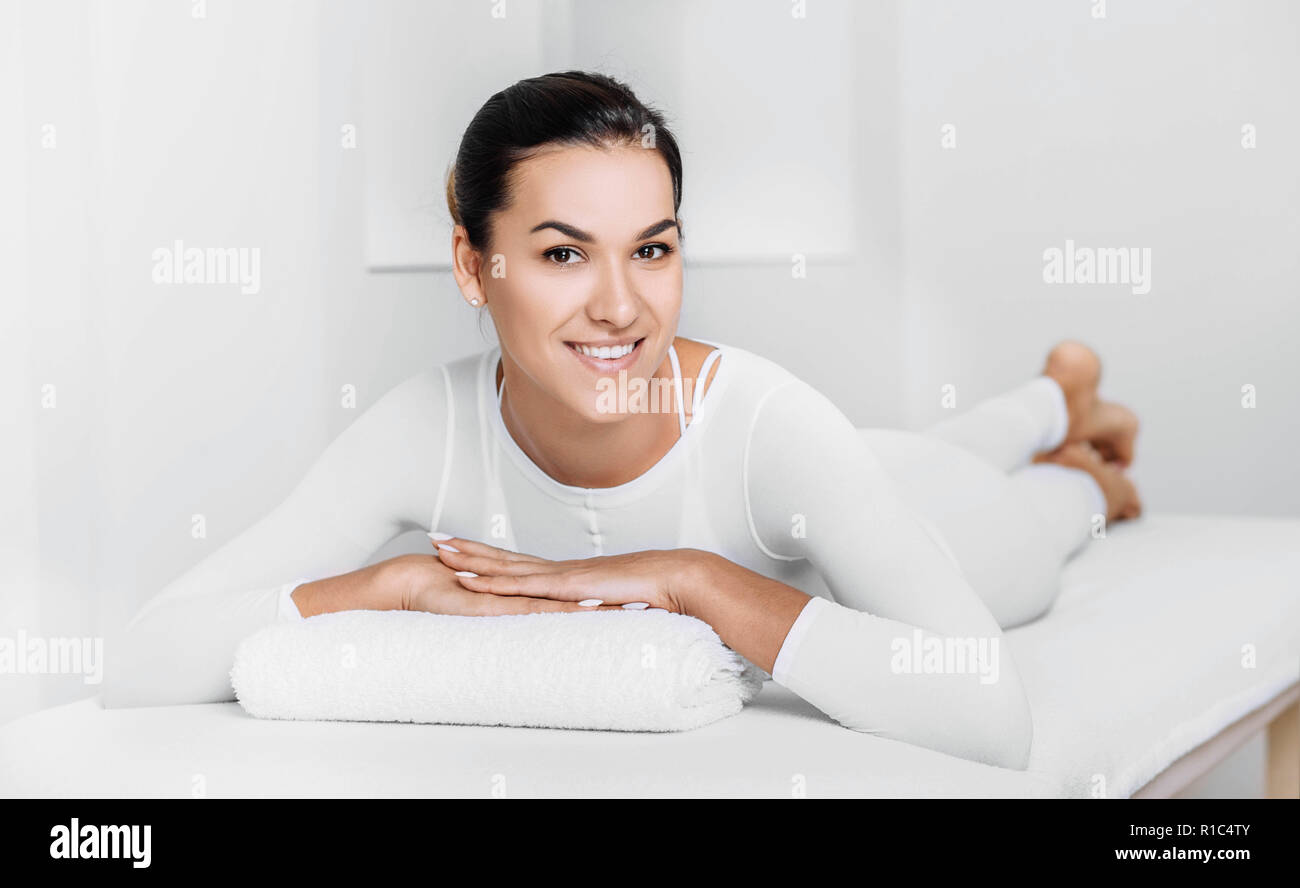 Beautiful happy woman lying on massage table after beauty therapy against cellulite with LPG machine. LPG massage for lifting body Stock Photo