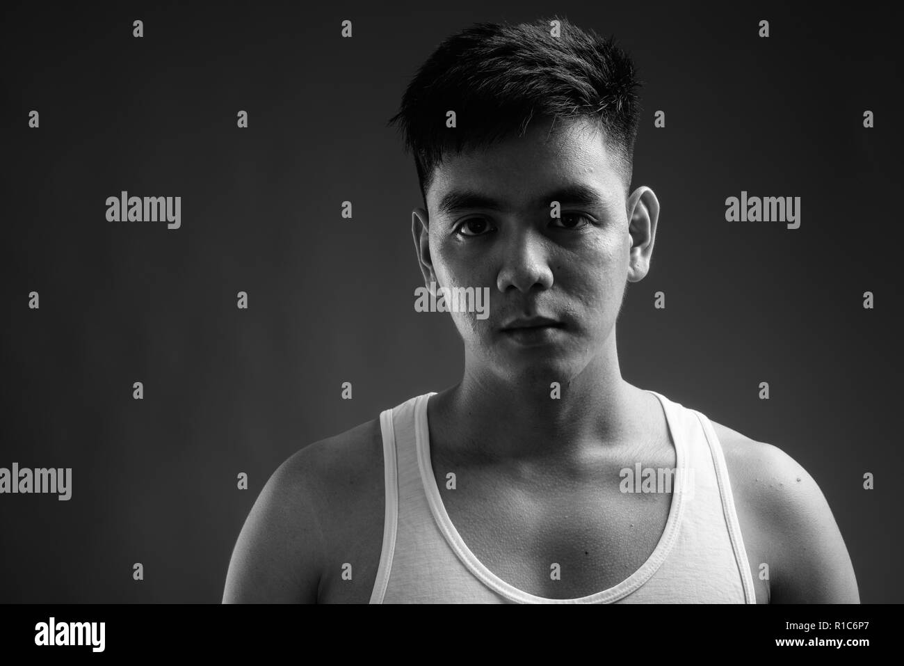 Young handsome Asian man wearing tank top against gray backgroun Stock Photo