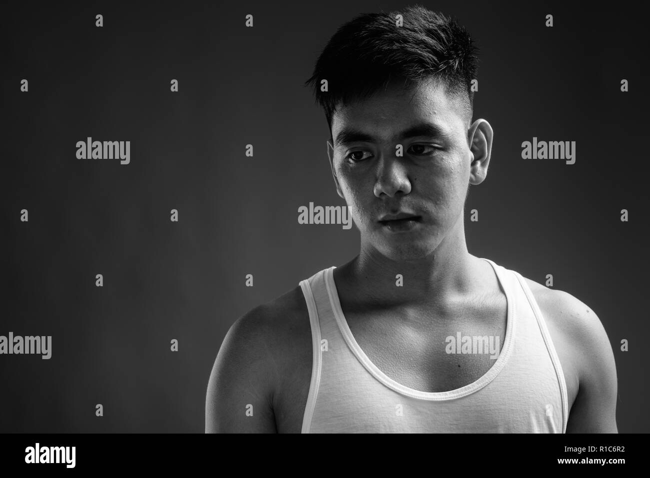 Young handsome Asian man wearing tank top against gray backgroun Stock Photo