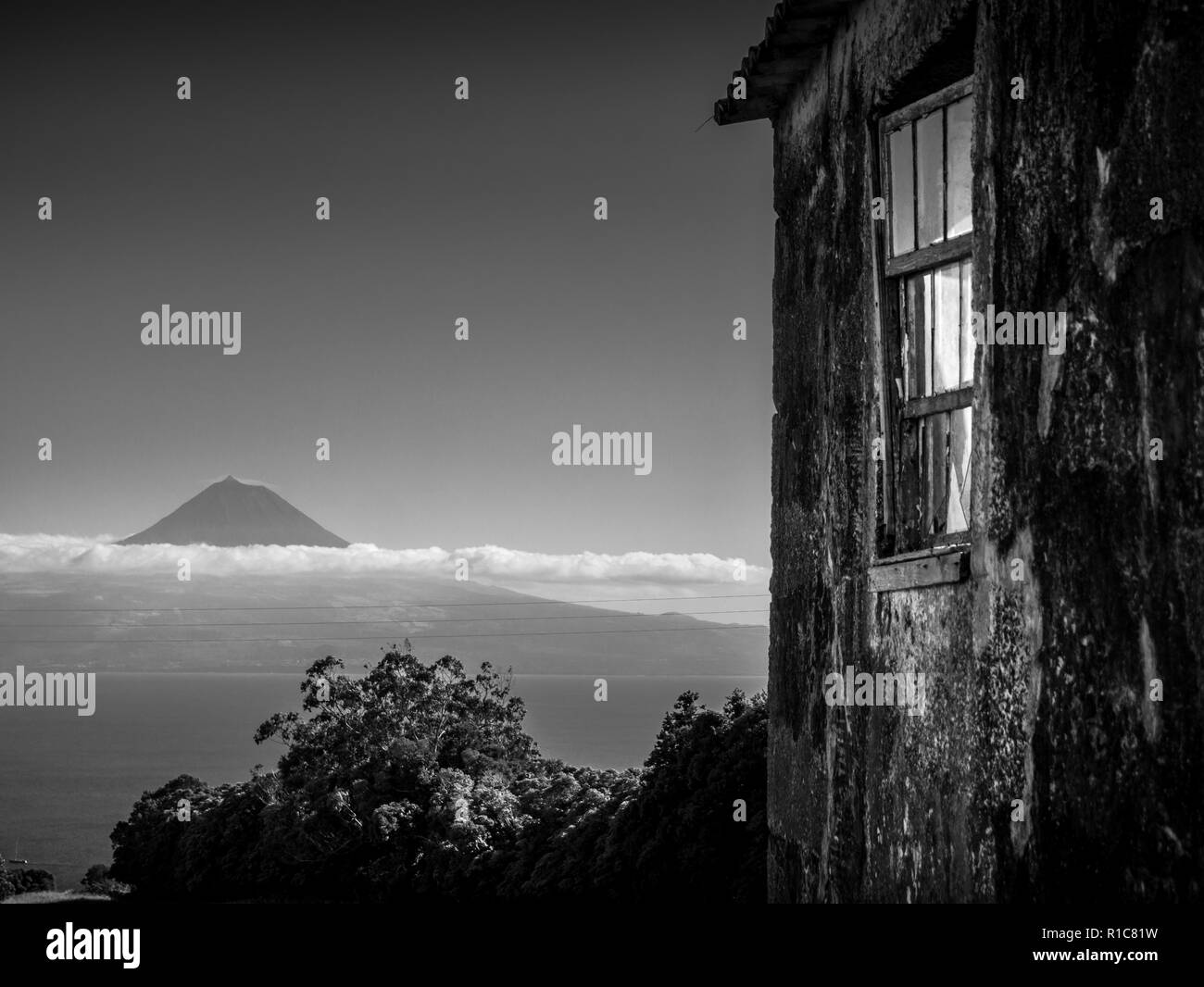 Black and white image of building in the foreground and the mountain of Pico in the background Azores Portugal Europe Stock Photo