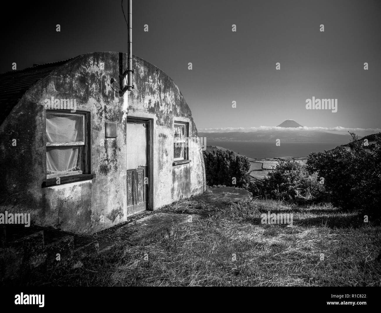 Black and white image of building in the foreground and the mountain of Pico in the background Azores Portugal Europe Stock Photo
