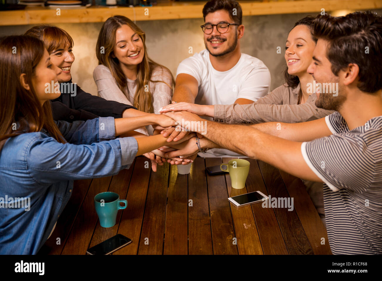 Group of friends joining their hands together at the cafe Stock Photo