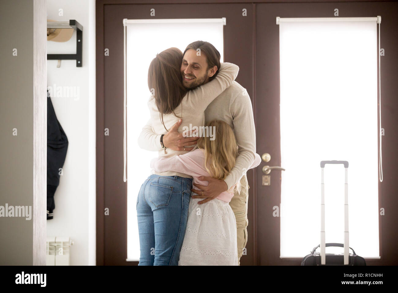 Happy family hugging in hallway at home Stock Photo