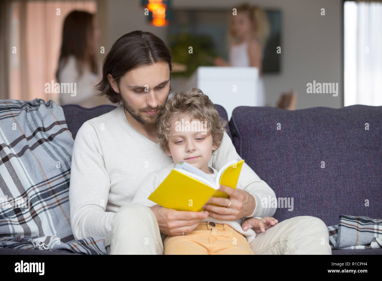 Father and son with fairytale book on couch Stock Photo