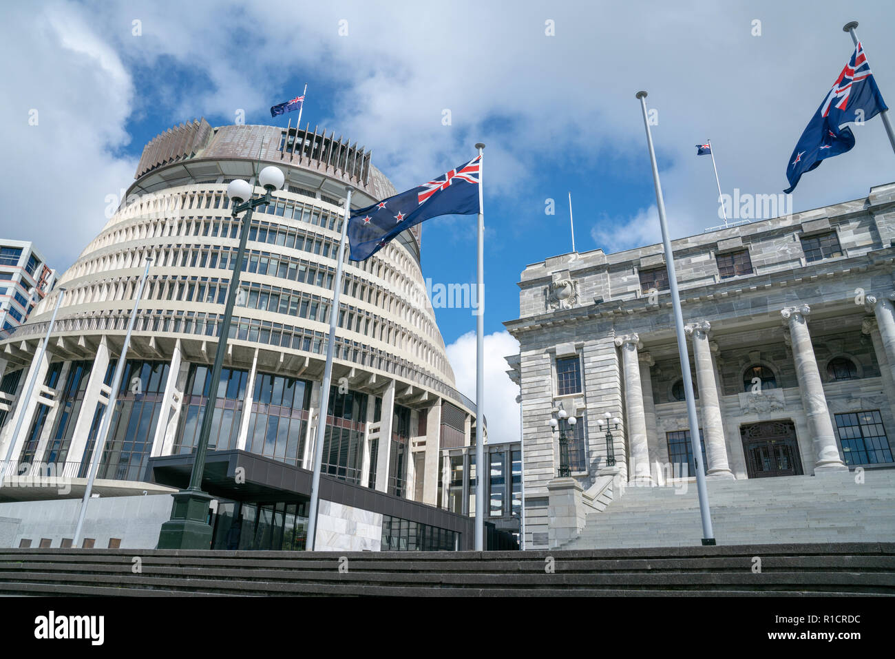 Flags flutter in front New Zealand Government buildings, House neo classical style House of Parliament with Beehive behind. Stock Photo