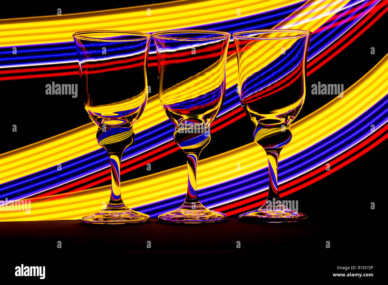Three elegant wine glass / glasses with streaks of neon light behind
