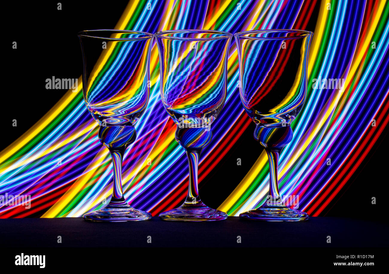 Three elegant wine glass / glasses with streaks of neon light behind