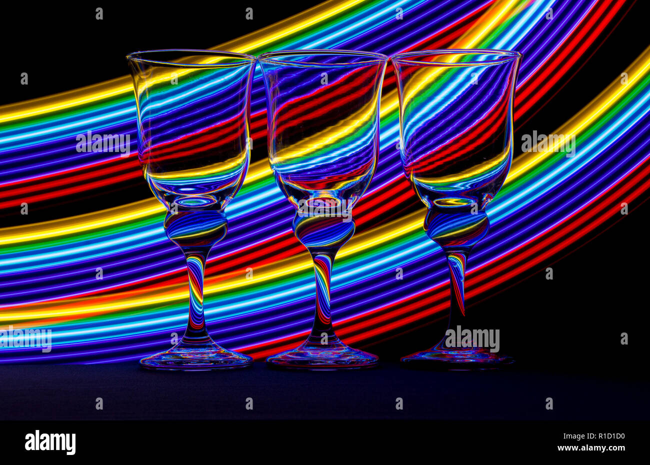 Three elegant wine glass / glasses with streaks of neon light behind