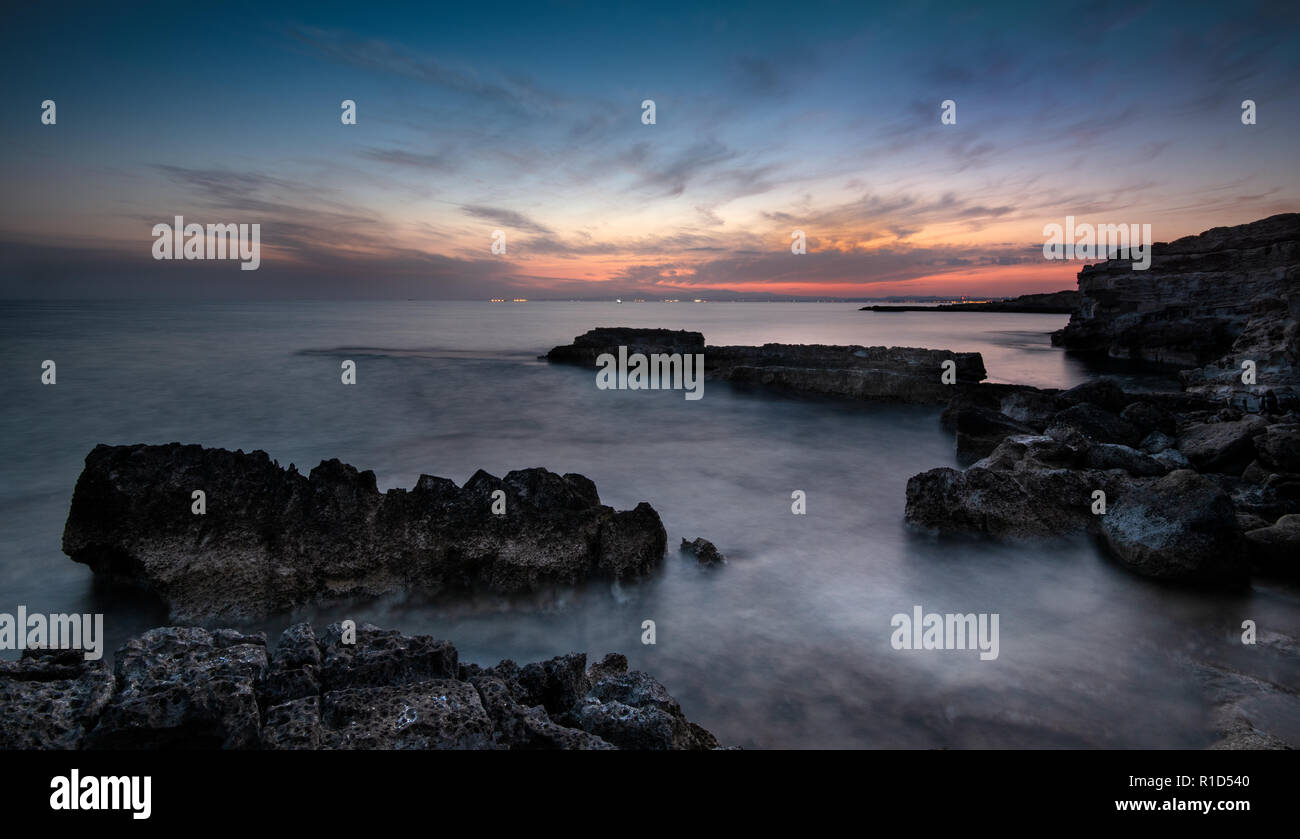 Dramatic sunset on a Rocky coastline with milky water  at Xylofagou area in Cyprus. Lond Exposure image Stock Photo