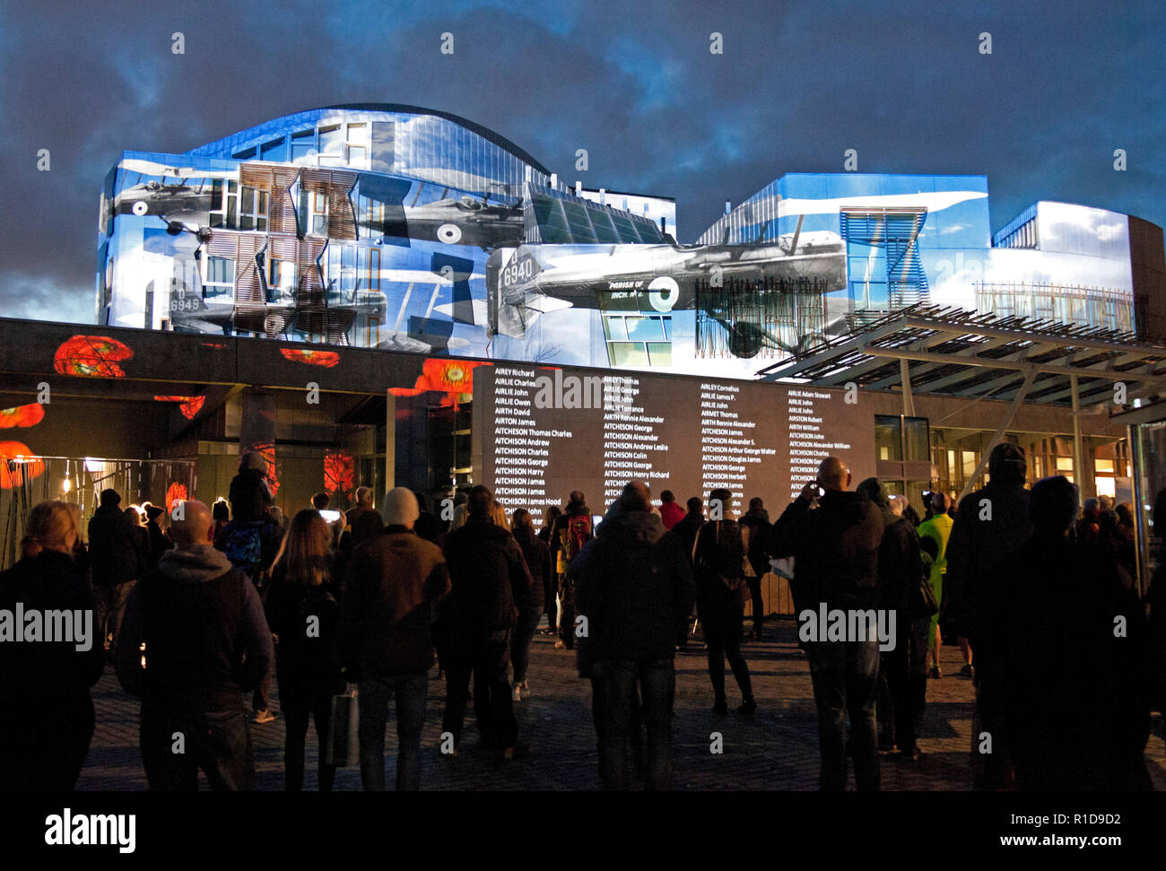Edinburgh Parliament, Scotland, UK. 11th Nov. 2018. Crowds begin to gather to view the Light and Sound Projection on the walls of the Scottish Parliament building on Remembrance Sunday at Holyrood to mark the 100th Anniversary of the Armistice, the event began at 5pm and continues for seven hours to allow the names of each of the 134,712 men and women listed in the Scottish National War Memorial Roll of Honour which will be shown on the outside the building. Stock Photo
