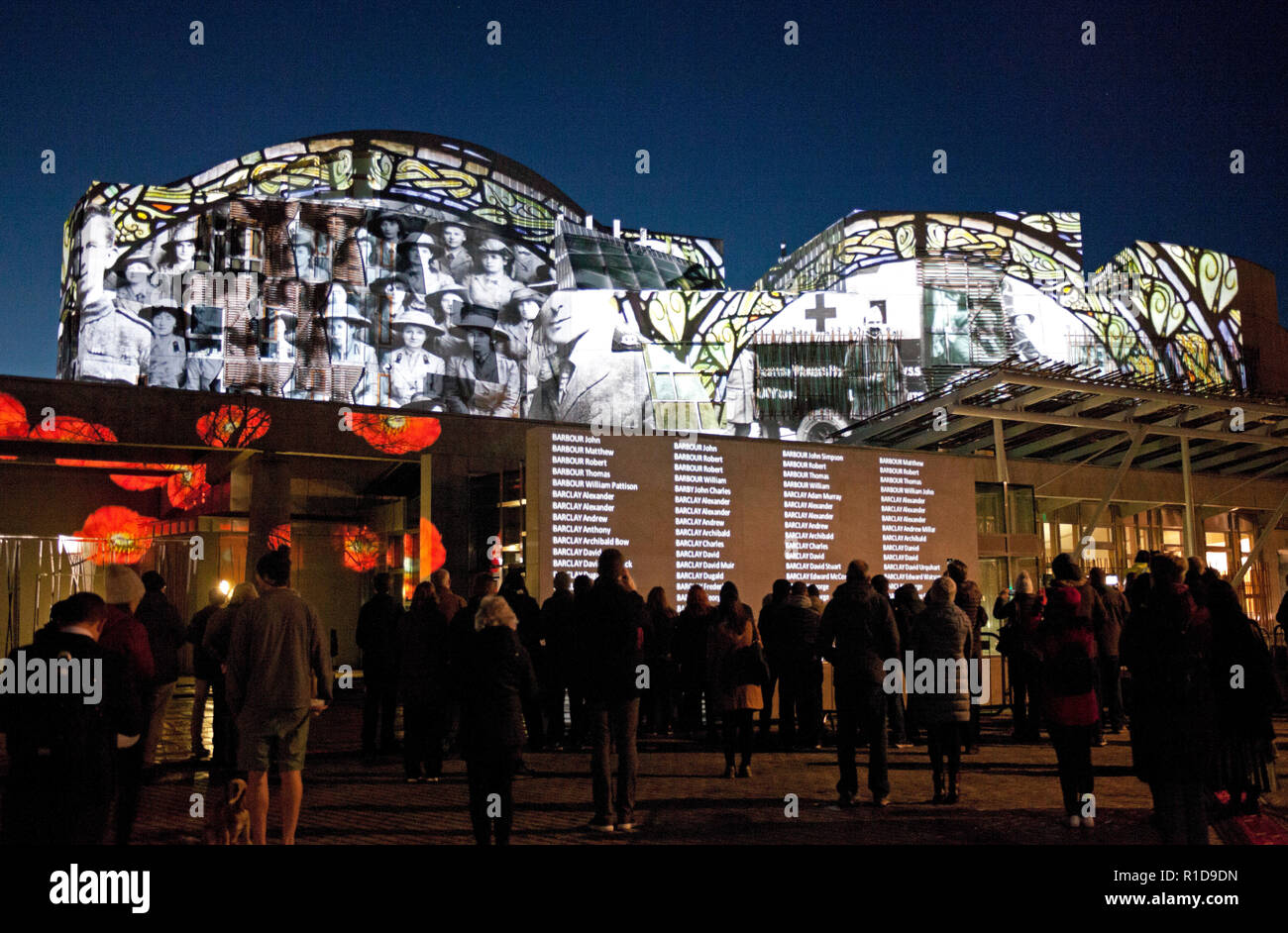 Edinburgh Parliament, Scotland, UK. 11th Nov. 2018. Crowds begin to gather to view the Light and Sound Projection on the walls of the Scottish Parliament building on Remembrance Sunday at Holyrood to mark the 100th Anniversary of the Armistice, the event began at 5pm and continues for seven hours to allow the names of each of the 134,712 men and women listed in the Scottish National War Memorial Roll of Honour which will be shown on the outside the building. Stock Photo