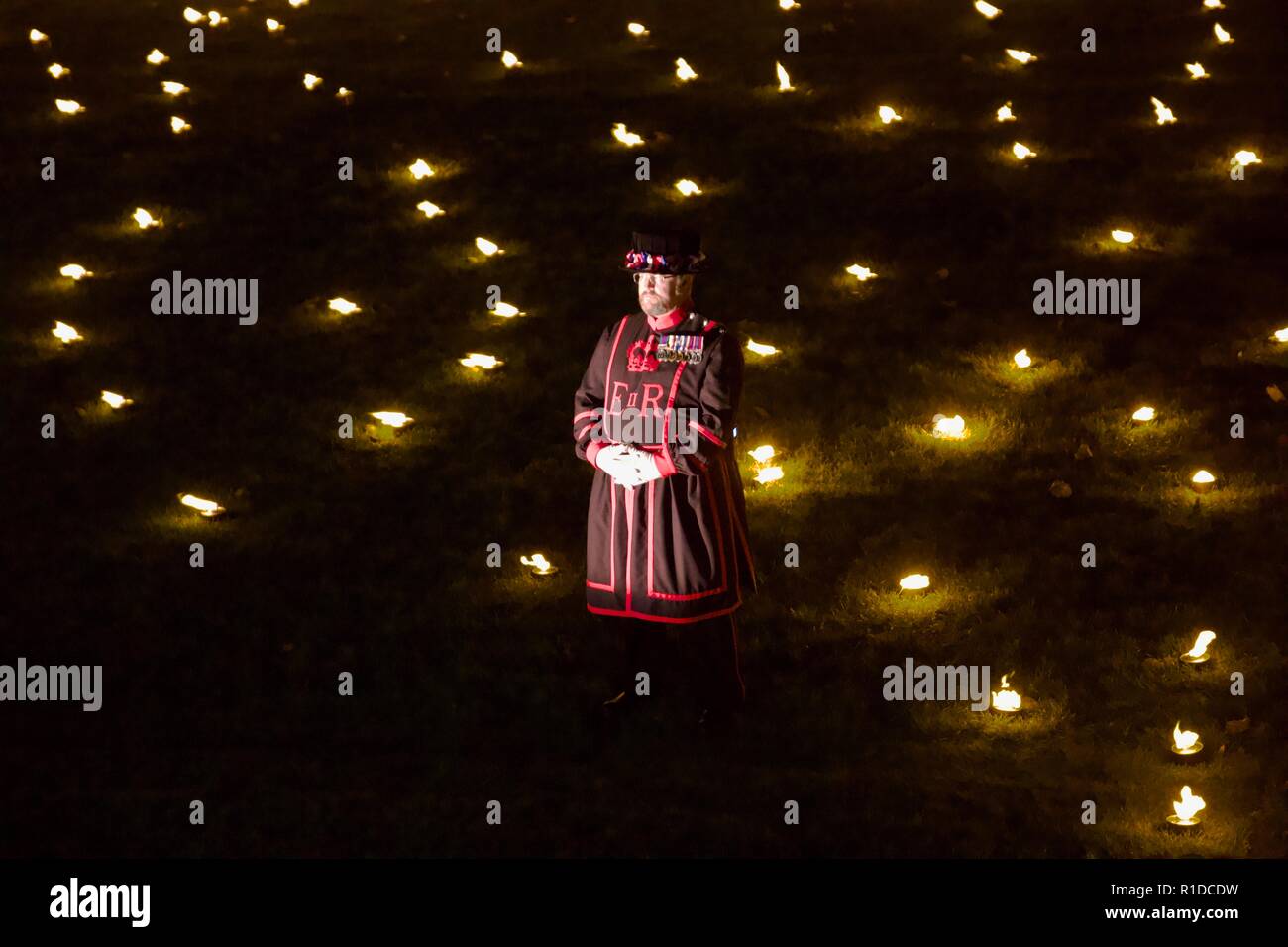 London, UK. 11th November 2018. Beefeater standing in the Tower of London moat. Beyond the Deepening Shadow is an installation where 10000 flames are lit for Rememberance Sunday. Credit: Dimple Patel/Alamy Live News Stock Photo