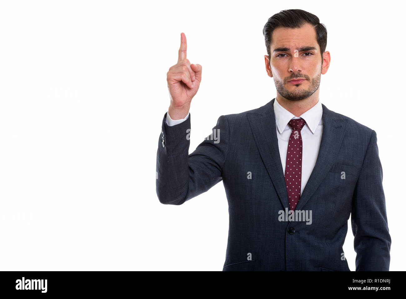 Studio shot of young handsome businessman pointing finger up  Stock Photo