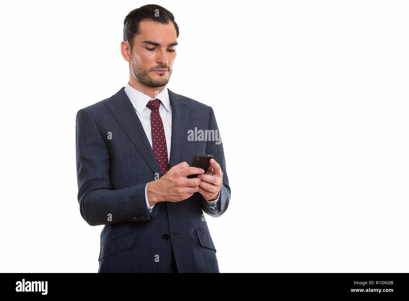 Studio shot of young handsome businessman using mobile phone wit Stock Photo