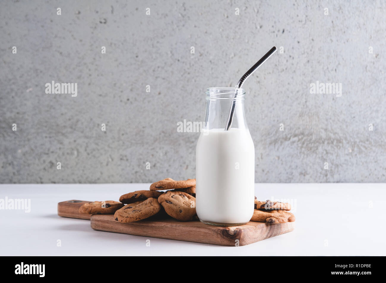 cookies and a bottle of milk with metal staws against a grey concreate background Stock Photo