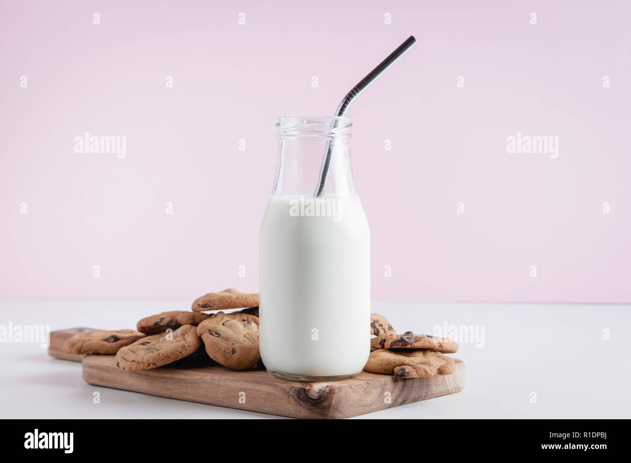 cokkies and a bottle of milk with metal straw on a pink background Stock Photo