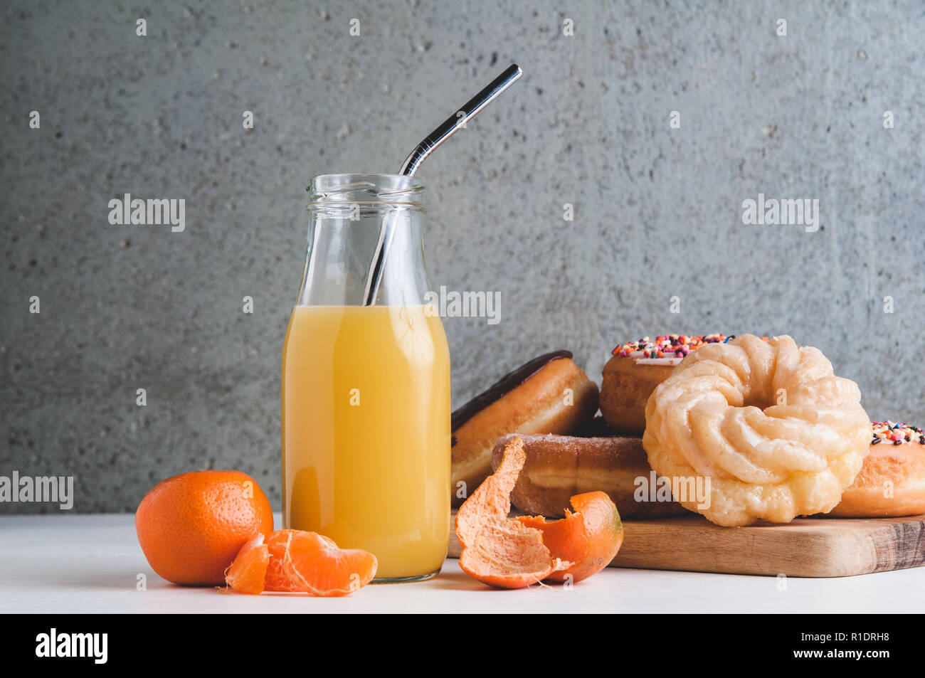 orange juice in a bottle and a platter of donuts Stock Photo