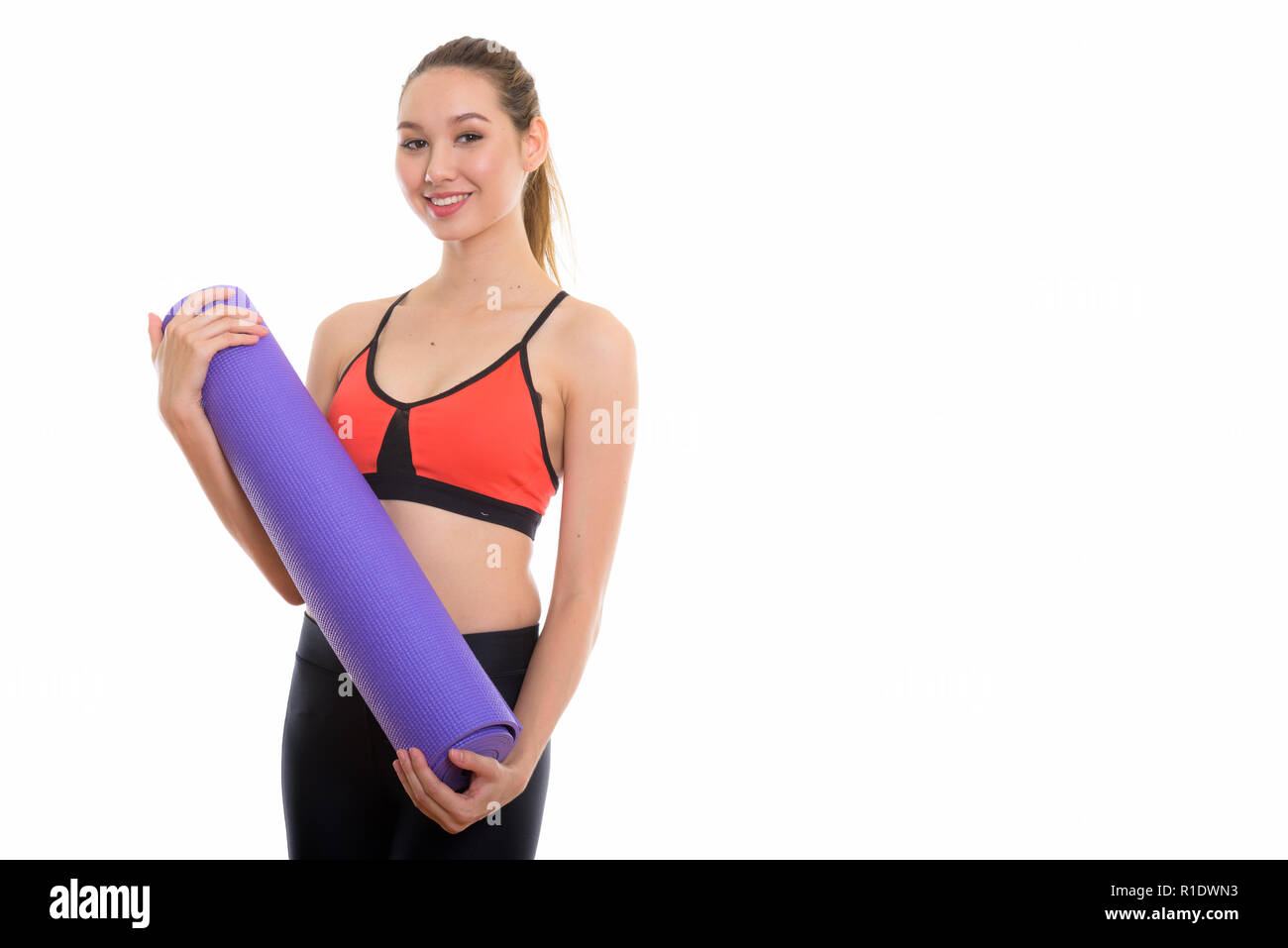 Studio shot of young happy beautiful Asian woman smiling while h Stock Photo