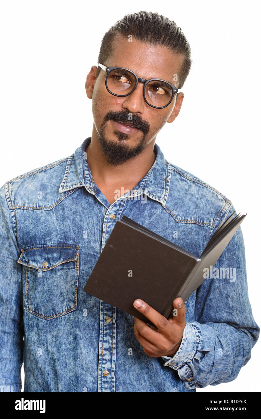 Young Indian man reading book while thinking Stock Photo