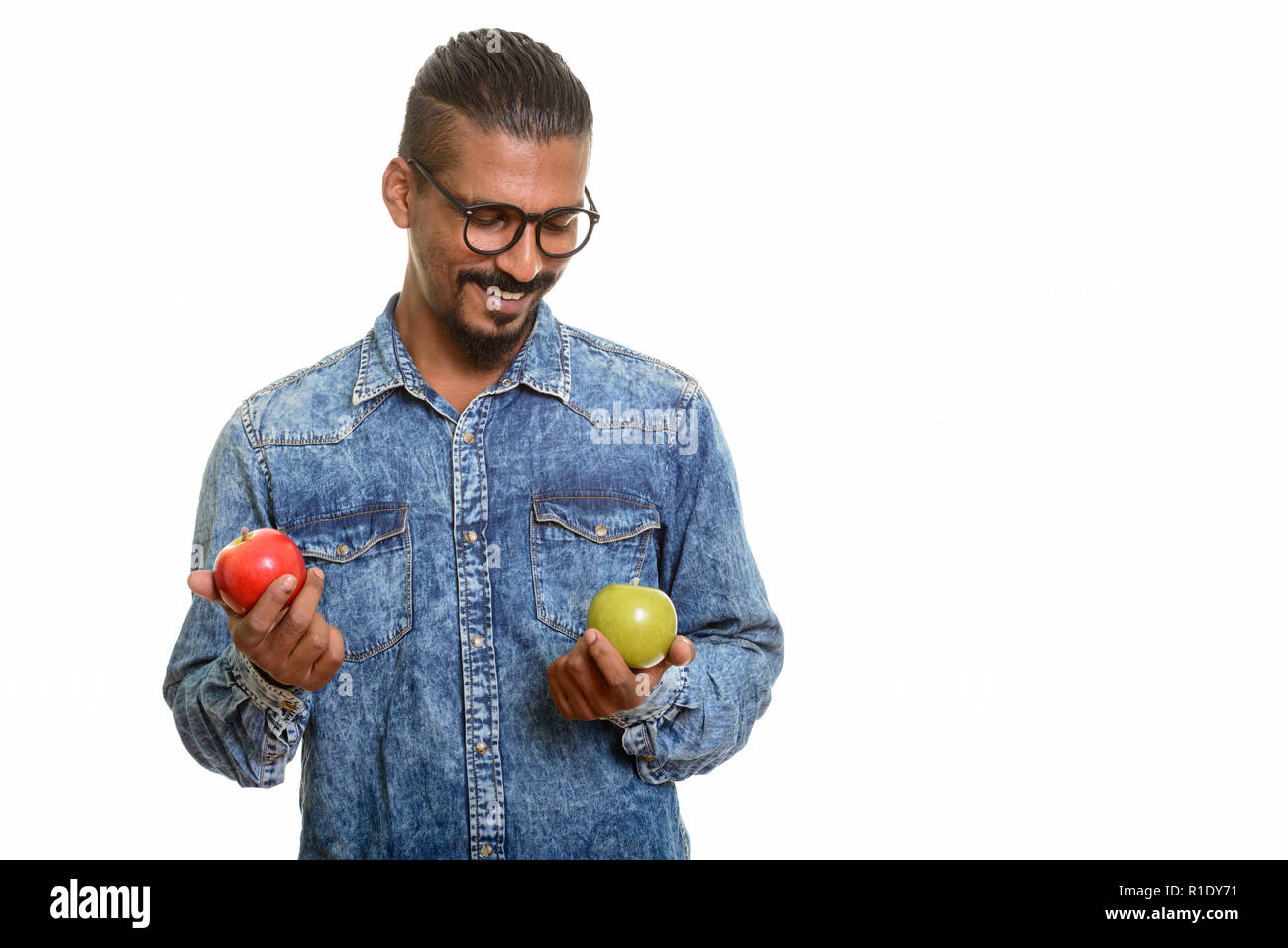 Young happy Indian man choosing between red and green apple Stock Photo ...