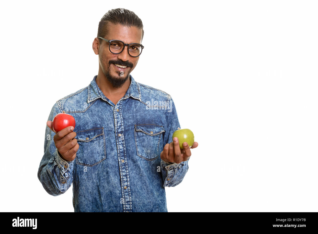 Young happy Indian man holding red and green apple Stock Photo - Alamy