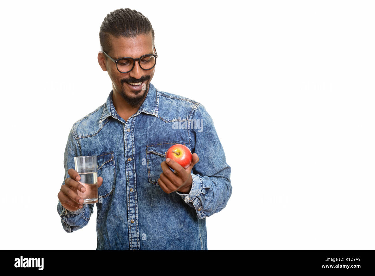 Young happy Indian man holding red apple and glass of water Stock Photo ...