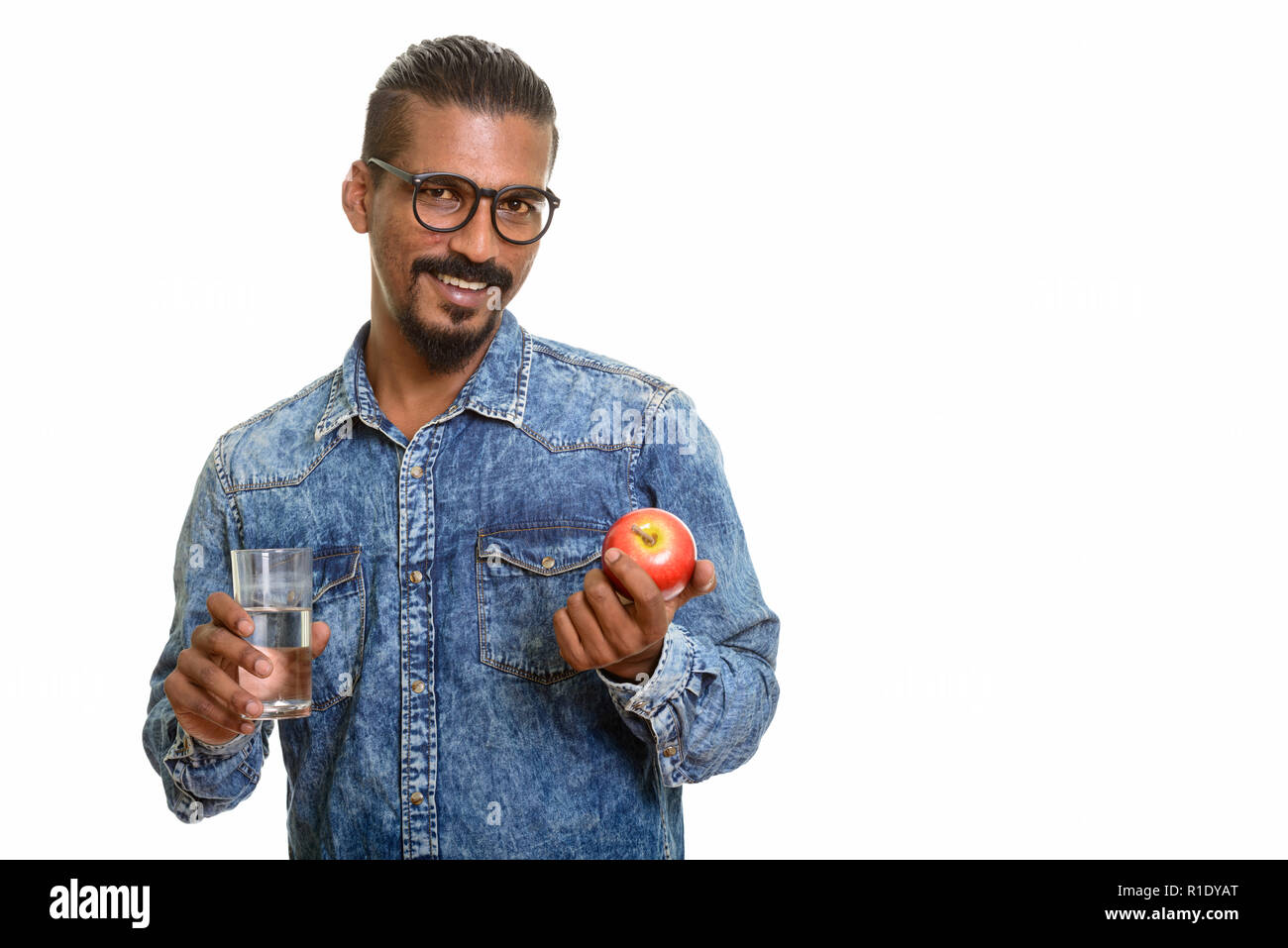 Young happy Indian man holding red apple and glass of water Stock Photo ...